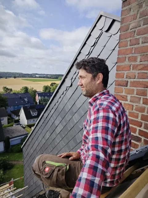 Dachdeckermeister Akbar Venn blickt über die Dächer in die Landschaft bei einer Pause